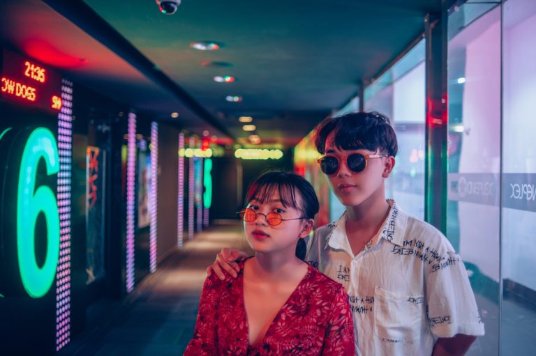 un ragazzo e una ragazza orientali all'interno di un cinema con luci e scritte al neon