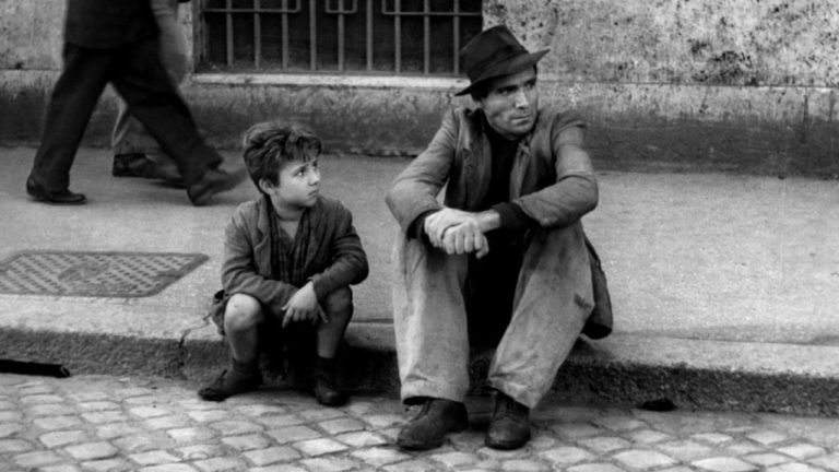 classici del cinema: padre e figlio siedono sul marciapiede in ladri di biciclette